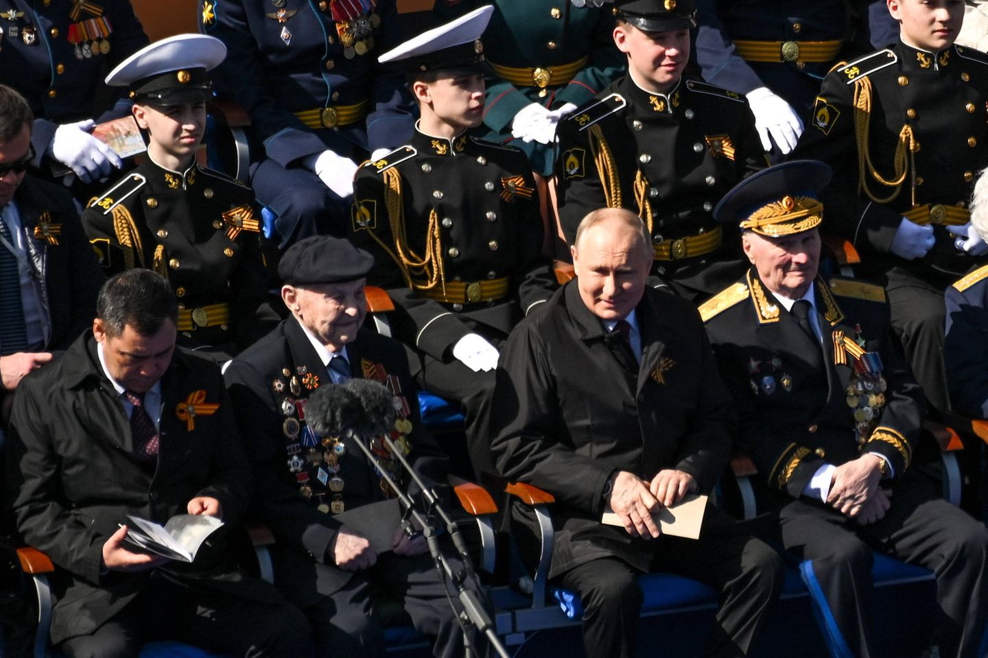 Auf der Tribüne nimmt Putin jedoch Platz zwischen Veteranen und Kadetten. 