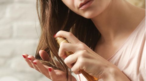 Eine Frau macht sich Haaröl in die Haarspitzen