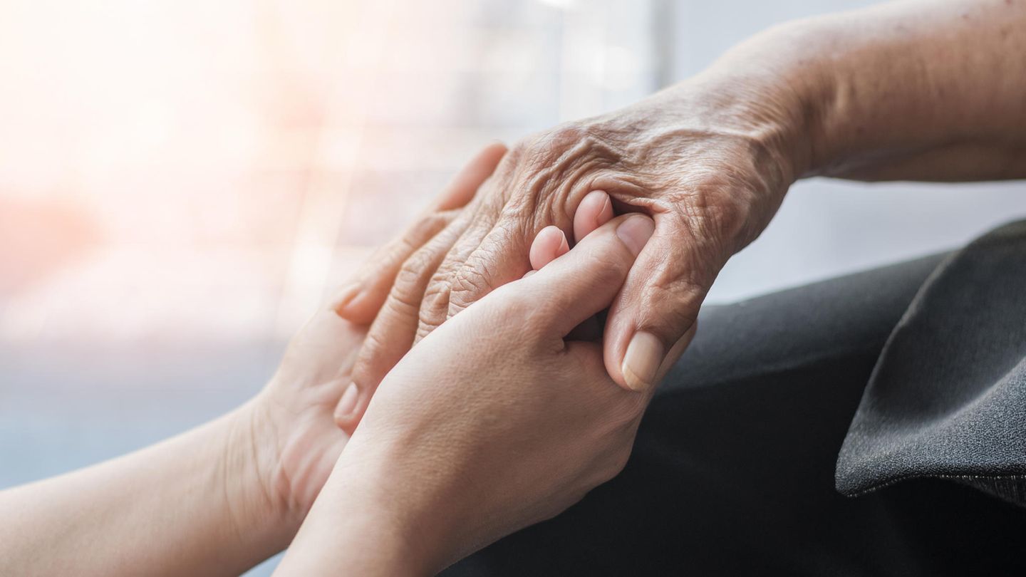 Zwei Menschen halten sich an den Händen. Death Doulas begleiten Sterbende in den Tod. Zwei Menschen halten sich an den Händen. Death Doulas begleiten Sterbende in den Tod.