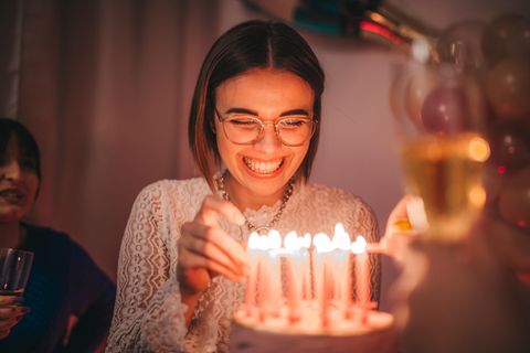 Eine Frau steht vor einem Kuchen mit Kerzen darauf