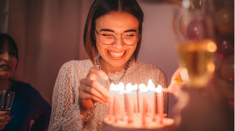 Eine Frau steht vor einem Kuchen mit Kerzen darauf
