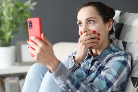 Frau schaut schockiert auf ihr Whatsapp-Smartphone