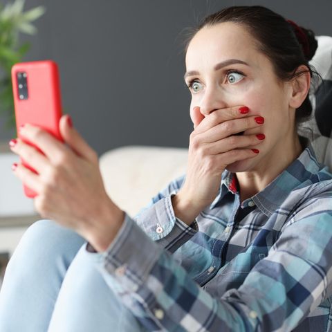Frau schaut schockiert auf ihr Whatsapp-Smartphone