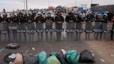 Venezolanische Migranten blockieren die Grenze mit Müll vor einer Barrikade der peruanischen Polizei