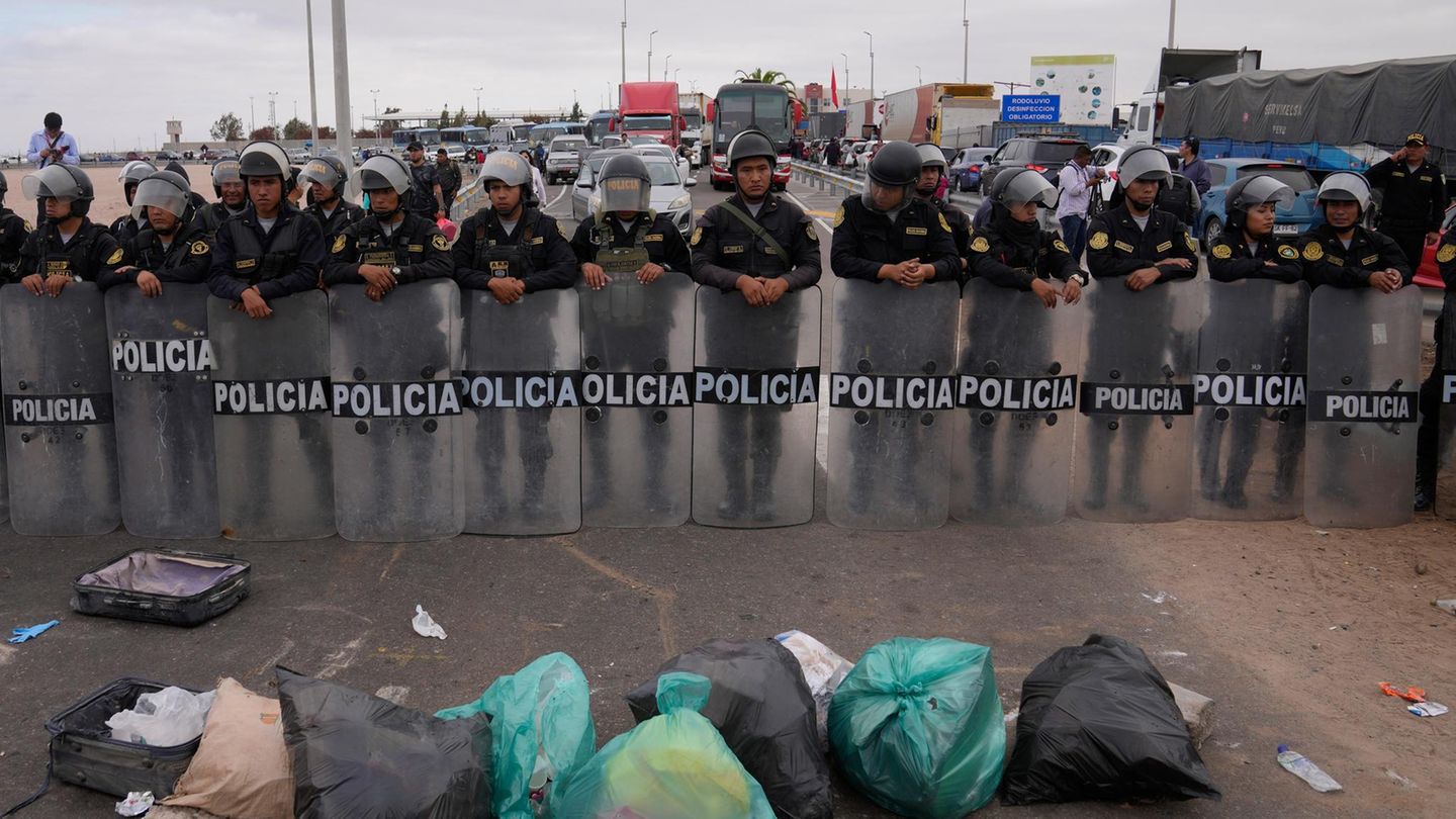 Venezolanische Migranten blockieren die Grenze mit Müll vor einer Barrikade der peruanischen Polizei