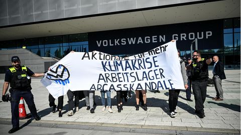 Aktivisten protestieren mit einem Banner vor dem Gebäude der VW-Hauptversammlung