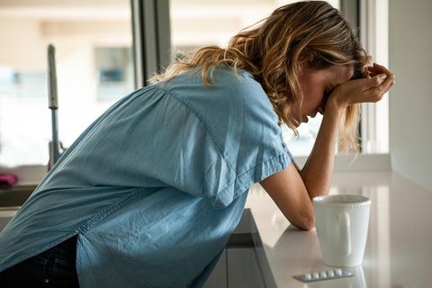 Frau mit Kopfschmerzen nimmt Schmerzmittel