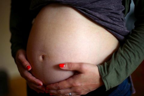 Eine schwangere Frau hält ihren Bauch