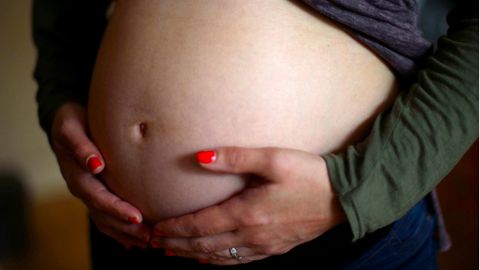 Eine schwangere Frau hält ihren Bauch