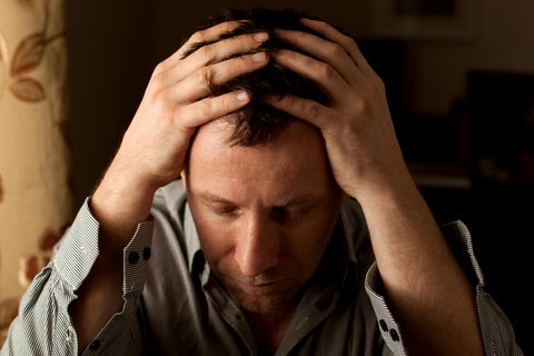 Ein Mann mit Clusterkopfschmerzen hält sich den Kopf