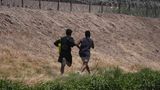Zwei junge Migranten aus Venezuela laufen bei Ciudad Juarez in Mexiko den Rio Bravo entlang, in der Hoffnung, über den Stacheldrahtzaun in die USA zu gelangen.
