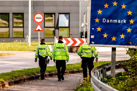Dänische Polizisten laufen an der deutsch/dänischen Grenze auf einem Fußgängerweg