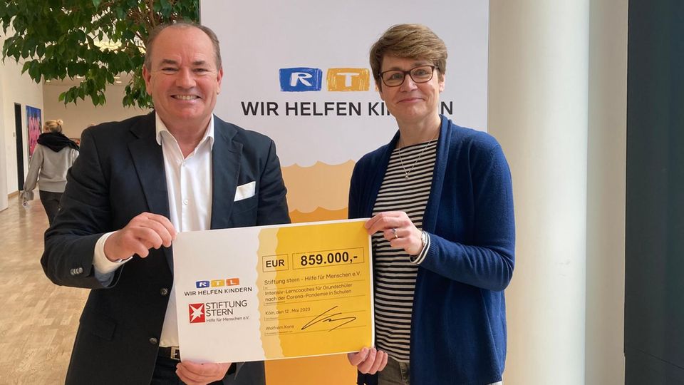 Wolfram Kons überreicht einen Scheck über 859.000 Euro an Catrin Boldebuck