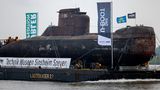 Das U-Boot auf einem Schwimmponton passiert auf dem Rhein den Ort Bimmen