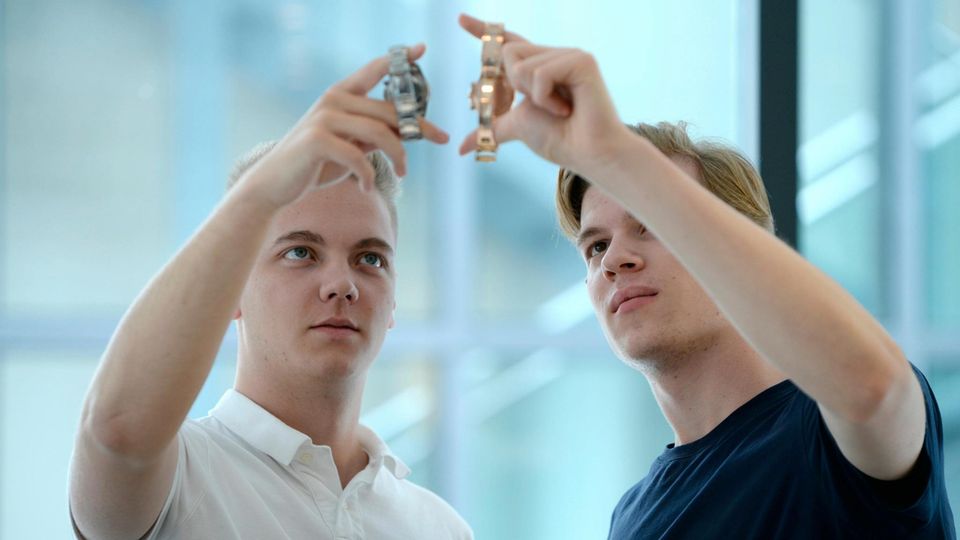 Zwei junge Männer halten Uhren in die Höhe