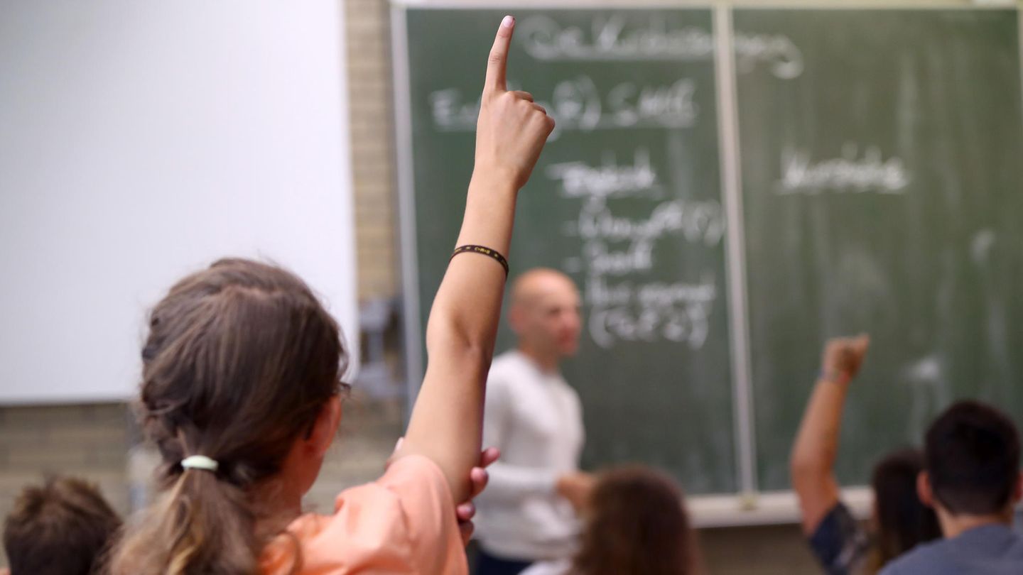 Education: Children in class raise hand in class