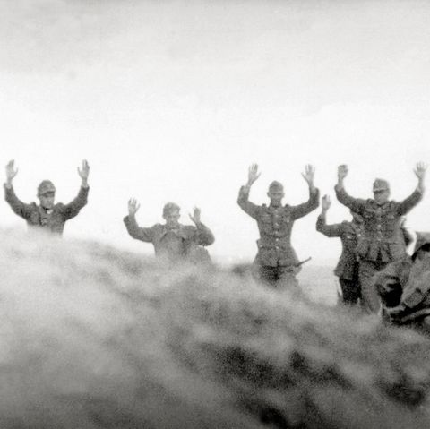 In Frankreich gehen Soldaten der Wehrmacht mit erhobenen Händen nebeneinander