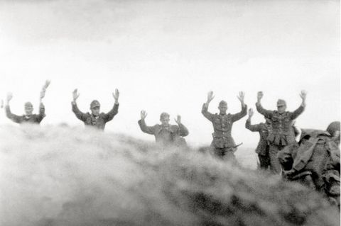 In Frankreich gehen Soldaten der Wehrmacht mit erhobenen Händen nebeneinander