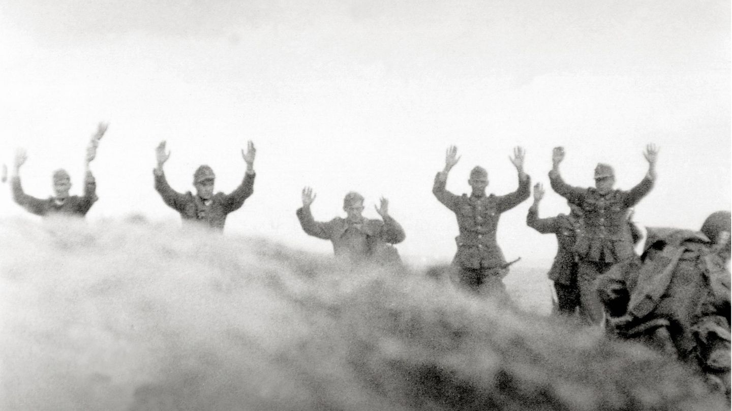 In Frankreich gehen Soldaten der Wehrmacht mit erhobenen Händen nebeneinander