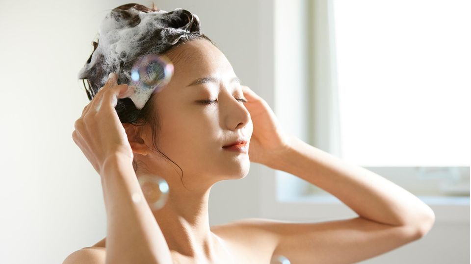Eine Frau wäscht sich die Haare mit Biotin Shampoo.