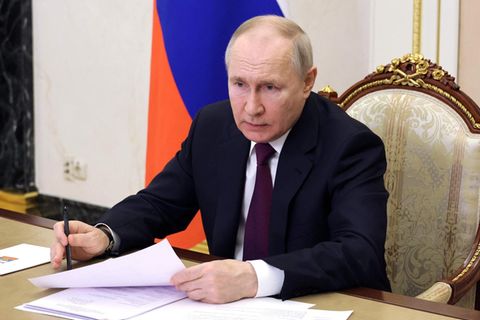 Russlands Präsident Wladimir Putin sitzt am schreibtisch