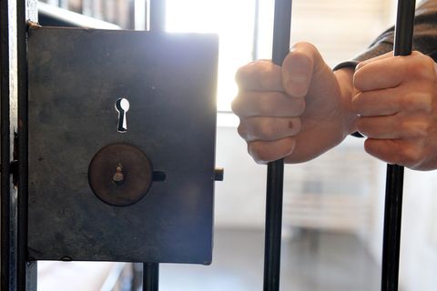 Eine Häftling umgreift die Gitterstäbe einer Tür. Großbritannien will Häftlinge aus dem Gefängnis abschieben.