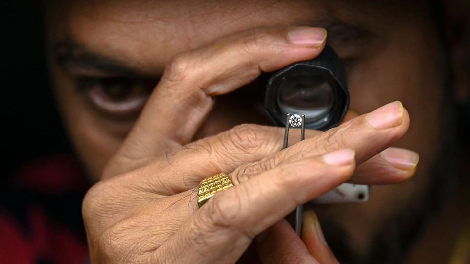 Ein Mann untersucht einen Diamanten mit einer Lupe