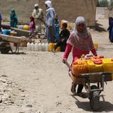 In Afghanistan schiebt ein Mädchen eine Sackkarre voller gelber und roter Wasserkanister