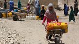 In Afghanistan schiebt ein Mädchen eine Sackkarre voller gelber und roter Wasserkanister