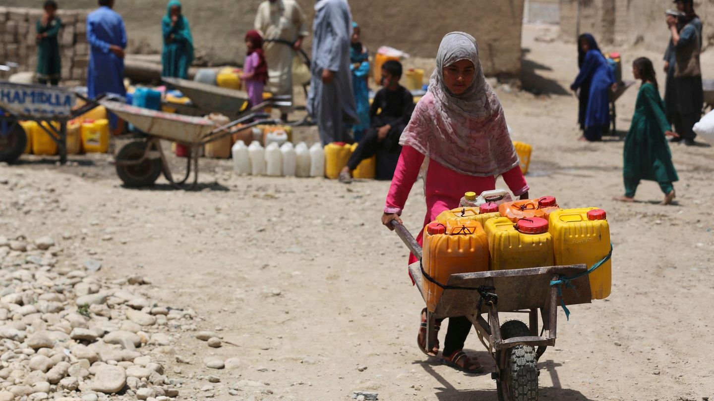 In Afghanistan schiebt ein Mädchen eine Sackkarre voller gelber und roter Wasserkanister