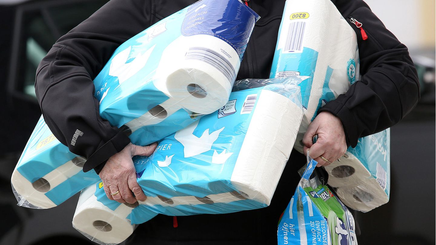 Ein Mann trägt mehrere Packungen Klopapier