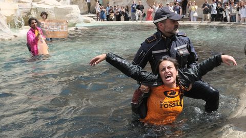 Klimaaktivisten der "Letzten Generation" werden von Polizisten aus dem Wasser des Trevi-Brunnen geleitet.