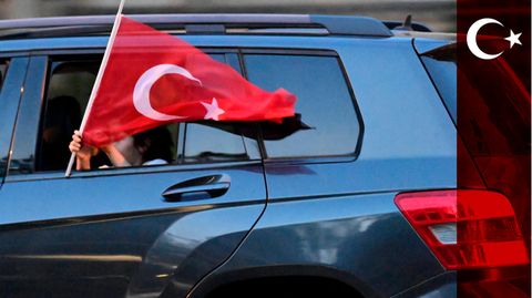 Ein Mädchen hält eine türkische Flagge aus einem Auto