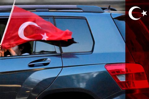 Ein Mädchen hält eine türkische Flagge aus einem Auto