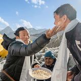 Ein Einheimischer reibt einem anderen Mann Getreide ins Gesicht