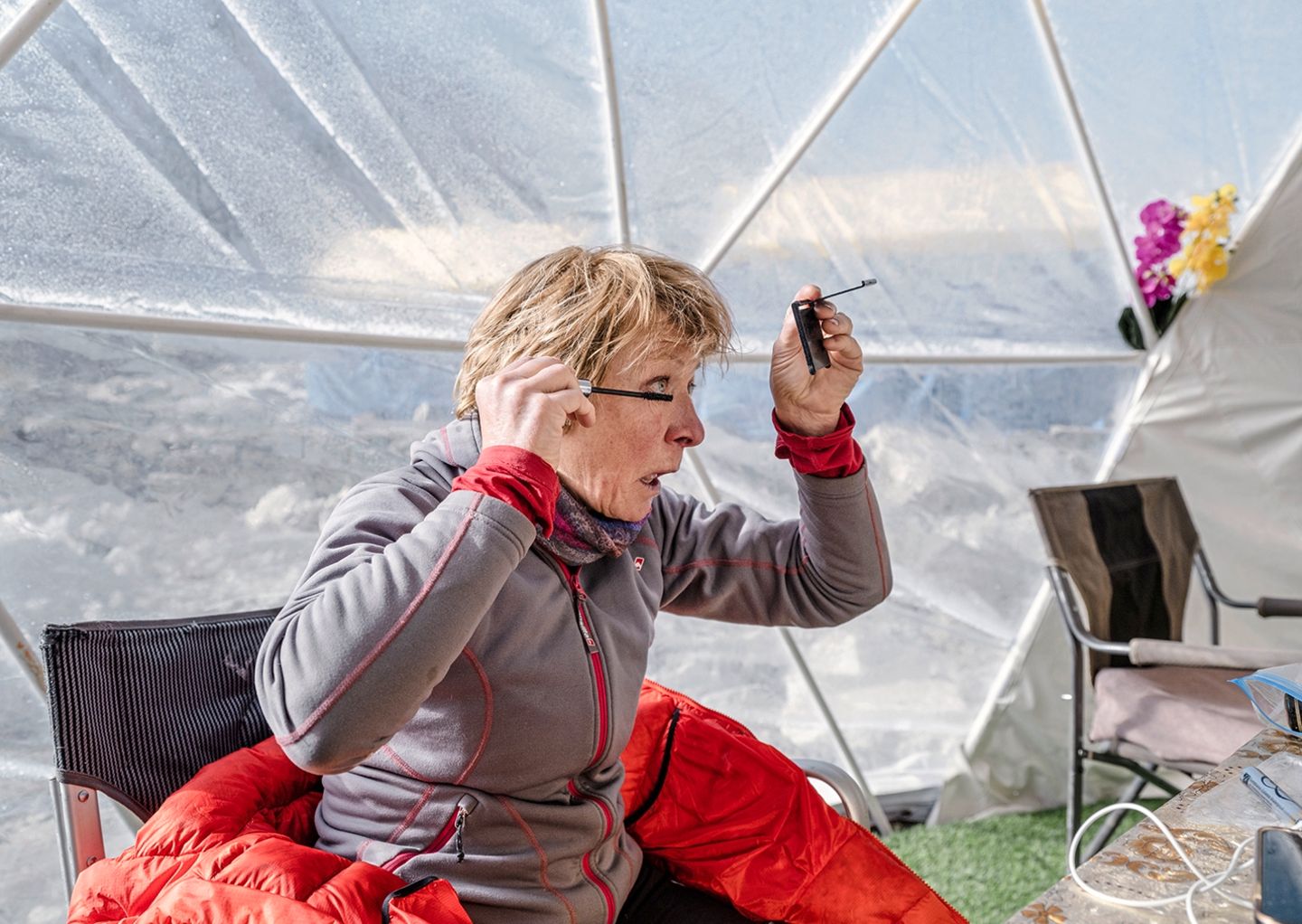 Eine Frau sitzt im Zelt und schminkt sich mit Wimperntusche