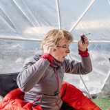 Eine Frau sitzt im Zelt und schminkt sich mit Wimperntusche