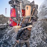 Ein Mann trägt eine riesige Menge an Utensilien für das Camp auf dem Rücken