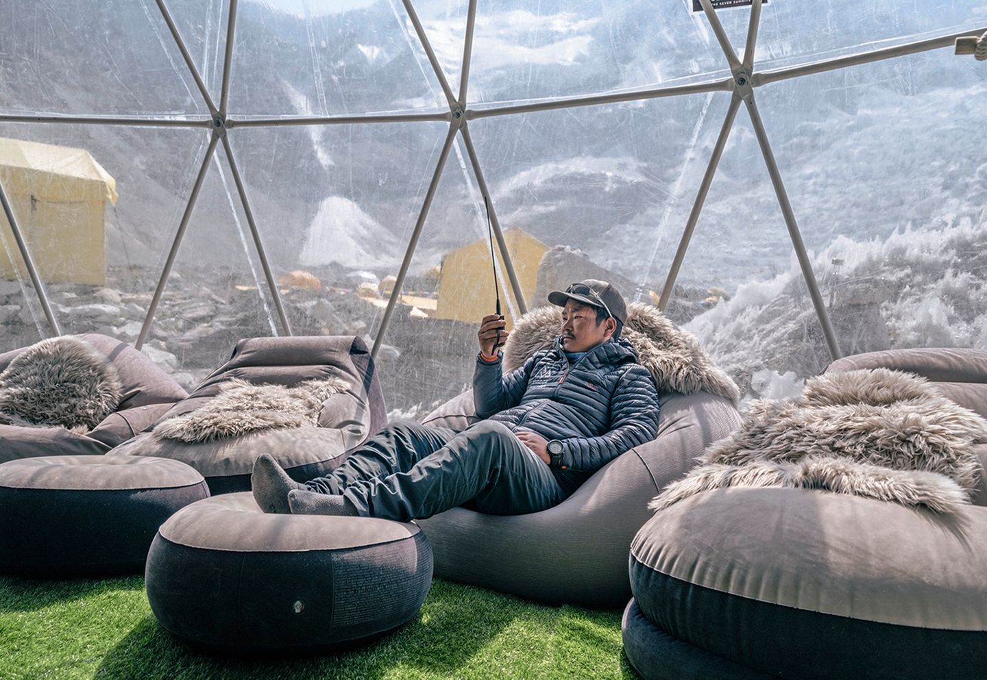 Sofas in einem Zelt mit transparenter Wand und den Bergen im Hintergrund
