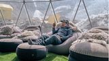 Sofas in einem Zelt mit transparenter Wand und den Bergen im Hintergrund