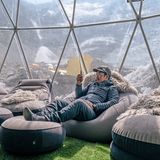 Sofas in einem Zelt mit transparenter Wand und den Bergen im Hintergrund