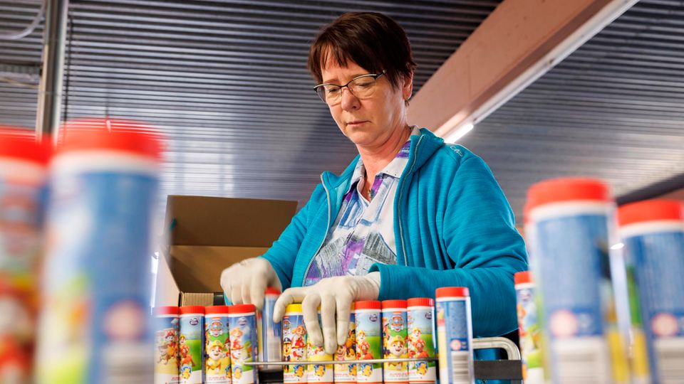 Eine Mitarbeiterin der Produktion sortiert Seifenblasendosen händisch in Kartons ein