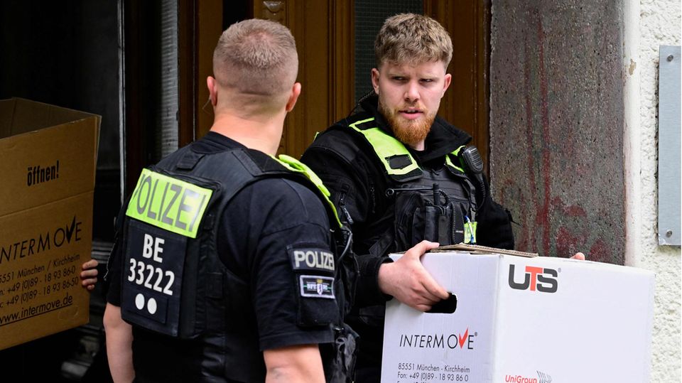 Ein Polizist trägt nach der Razzia gegen die "Letzte Generation" einen Karton aus einem Haus in Berlin-Kreuzberg