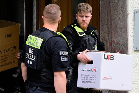 Ein Polizist trägt nach der Razzia gegen die "Letzte Generation" einen Karton aus einem Haus in Berlin-Kreuzberg