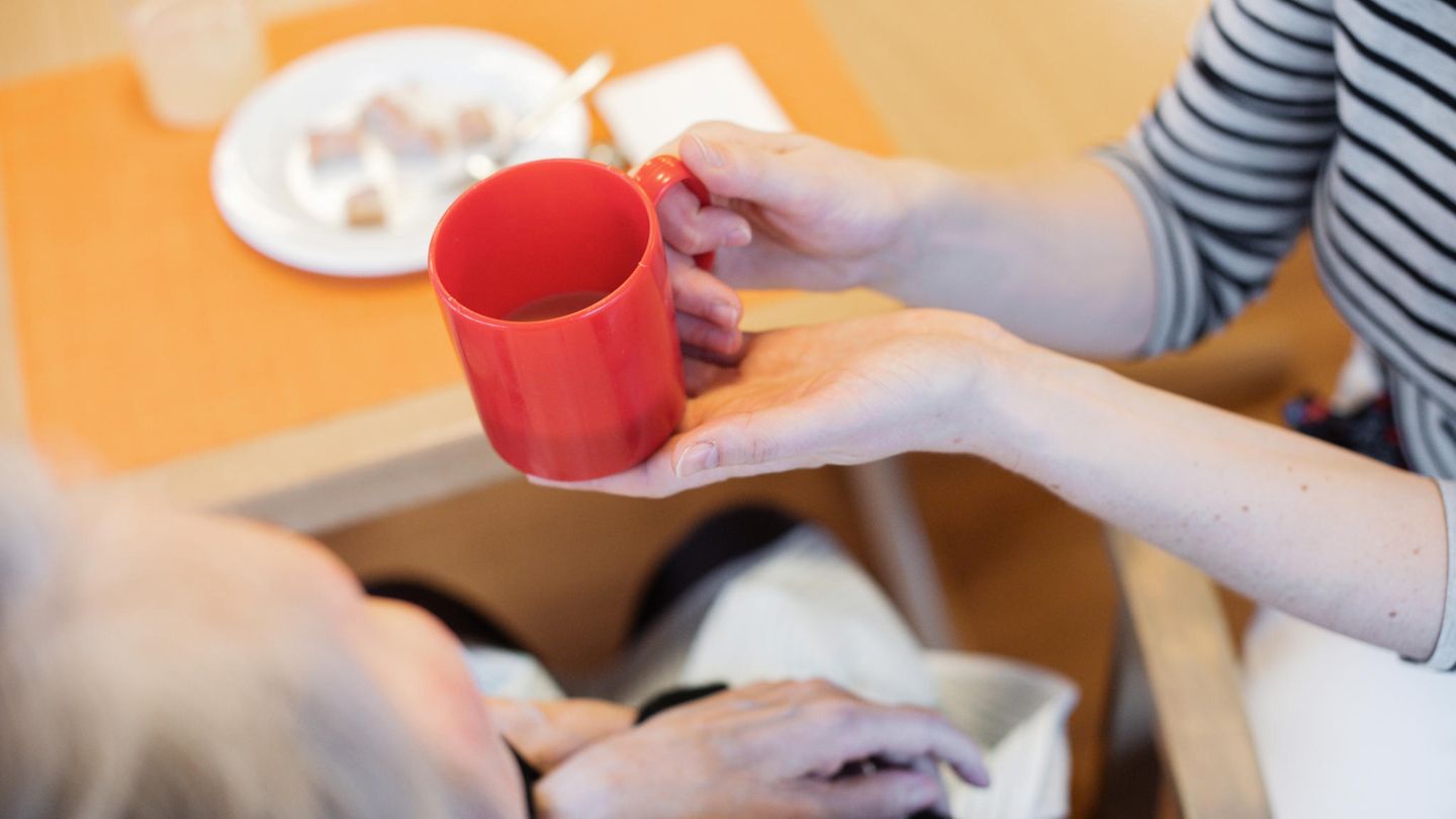 Eine Pflegerin reicht einer Frau ein Getränk. Bundesgesundheitsminister Karl Lauterbach will Pflegebedürftige entlasten