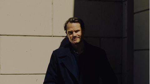 Fabian Hinrichs in schwarz gekleidet, halb im Schatten