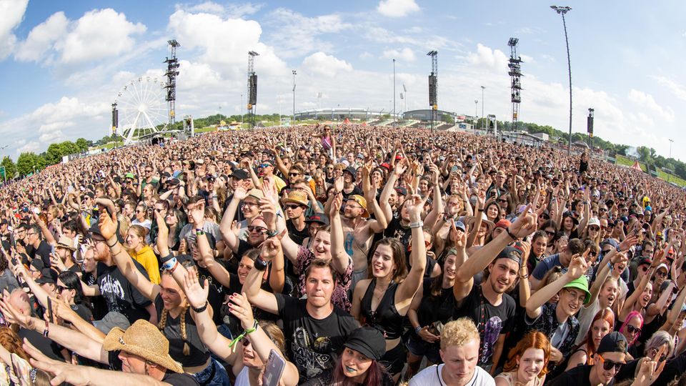 Menschen jubeln mit erhobenen Armen einer Band auf einem Festival zu