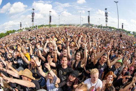 Menschen jubeln mit erhobenen Armen einer Band auf einem Festival zu