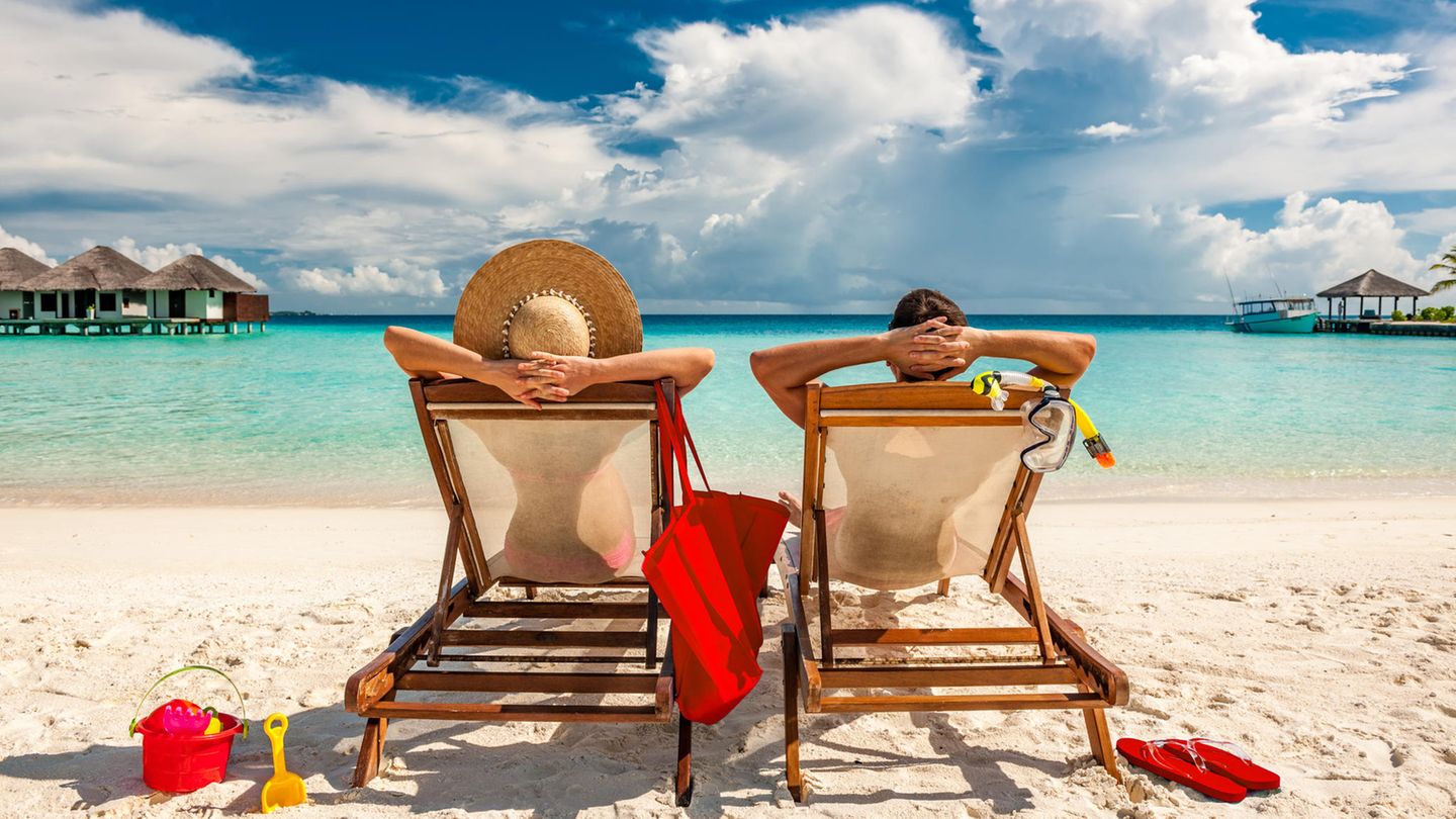 Packliste Strandurlaub Zwei Menschen liegen am Strand und sonnen sich.