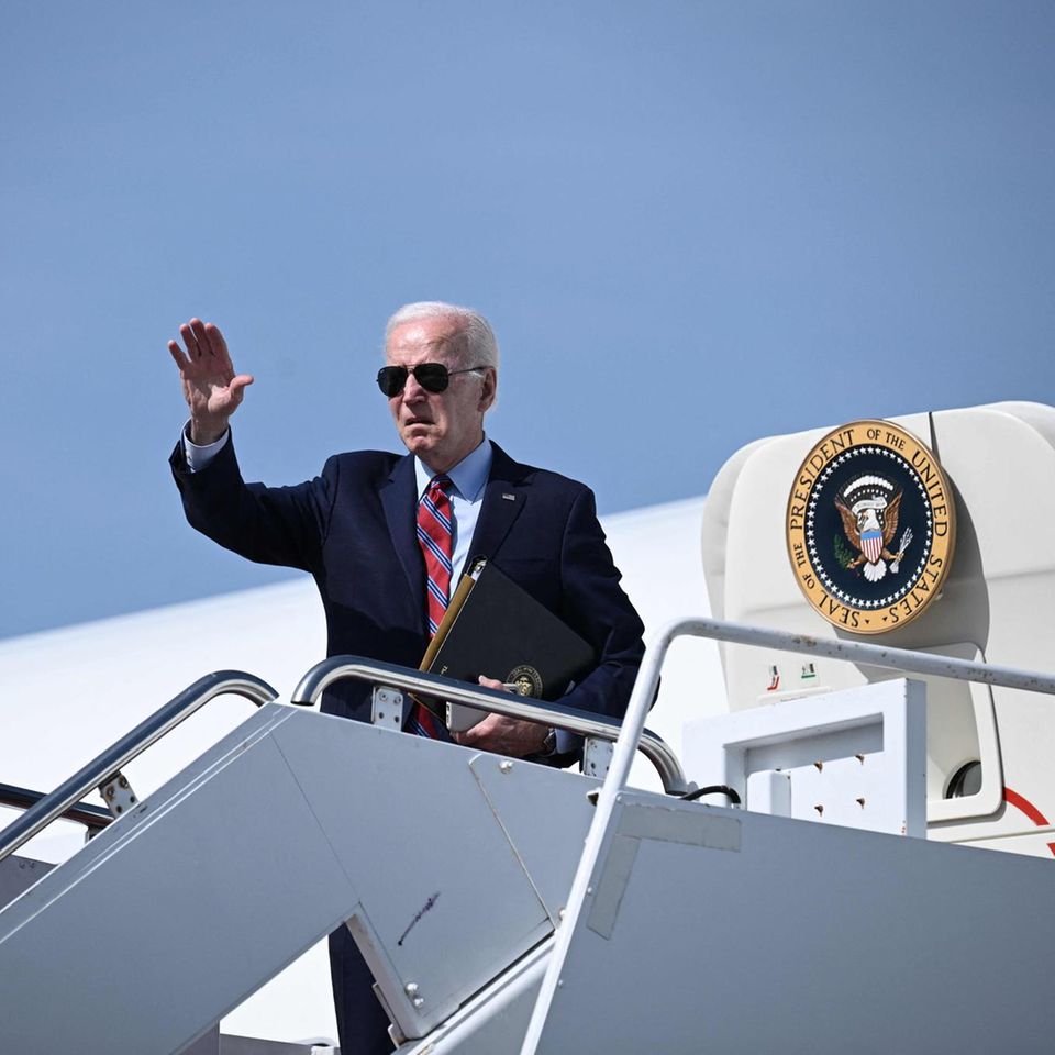 US-Pärsident Joe Biden steht auf der Gangway der Air Force One und winkt. Er trägt Anzug und Sonnenbrille sowie eine Mappe